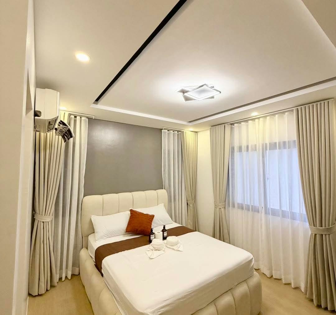A cream upholstered bed with warm lighting and floor-length curtains at The Cavin’s Cabin