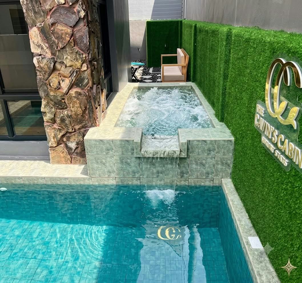 Bubbling jacuzzi spilling into the pool beside The Cavin’s Cabin sign