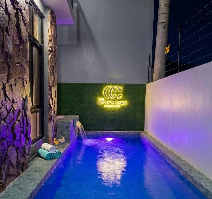The private pool glowing blue at night beside the stone facade